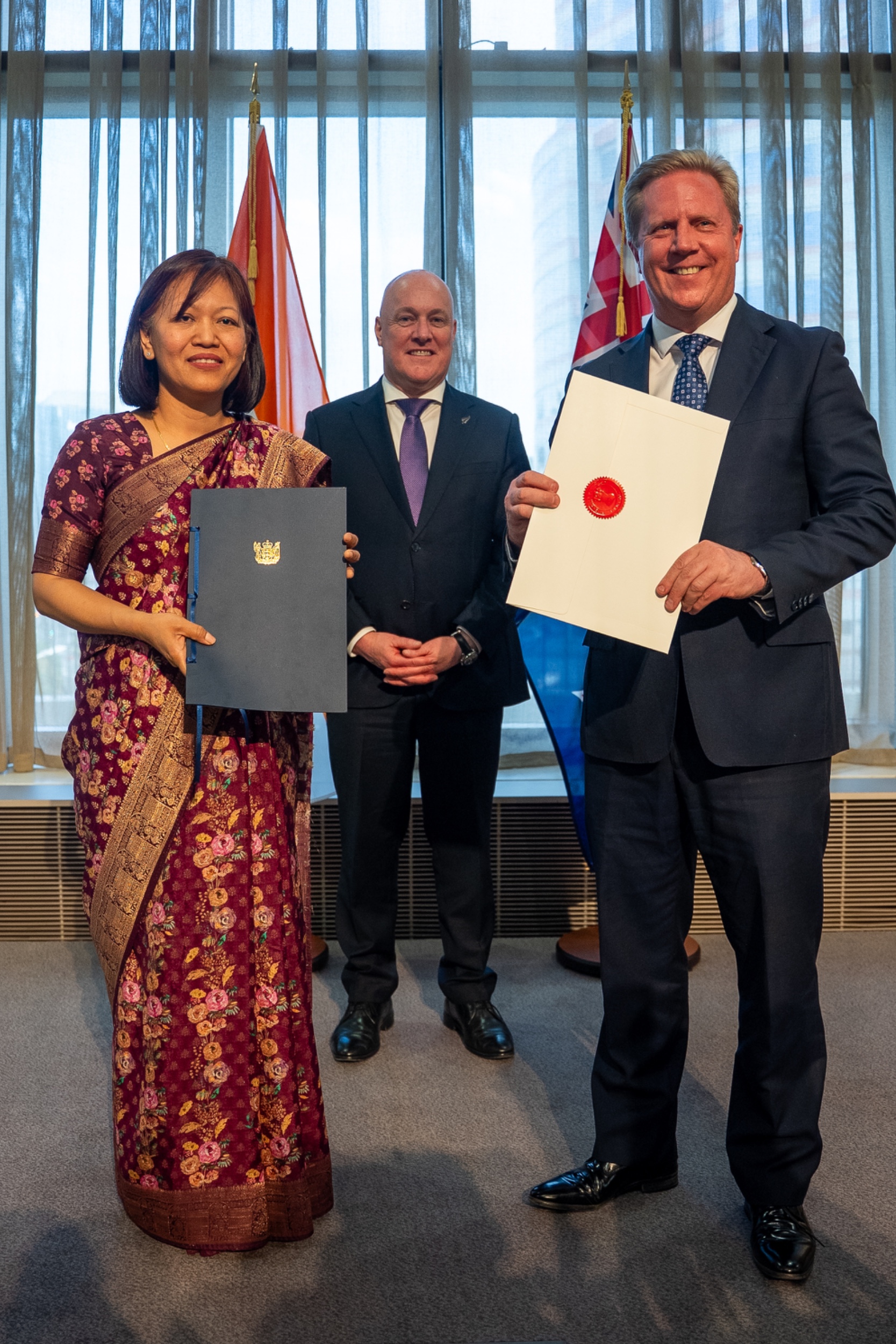Trade minister Todd McClay exchanges ratification documents with India's high commissioner Muanpuii Saiawi in Wellington on September 21, 2026, as prime minister Christopher Luxon looks on.