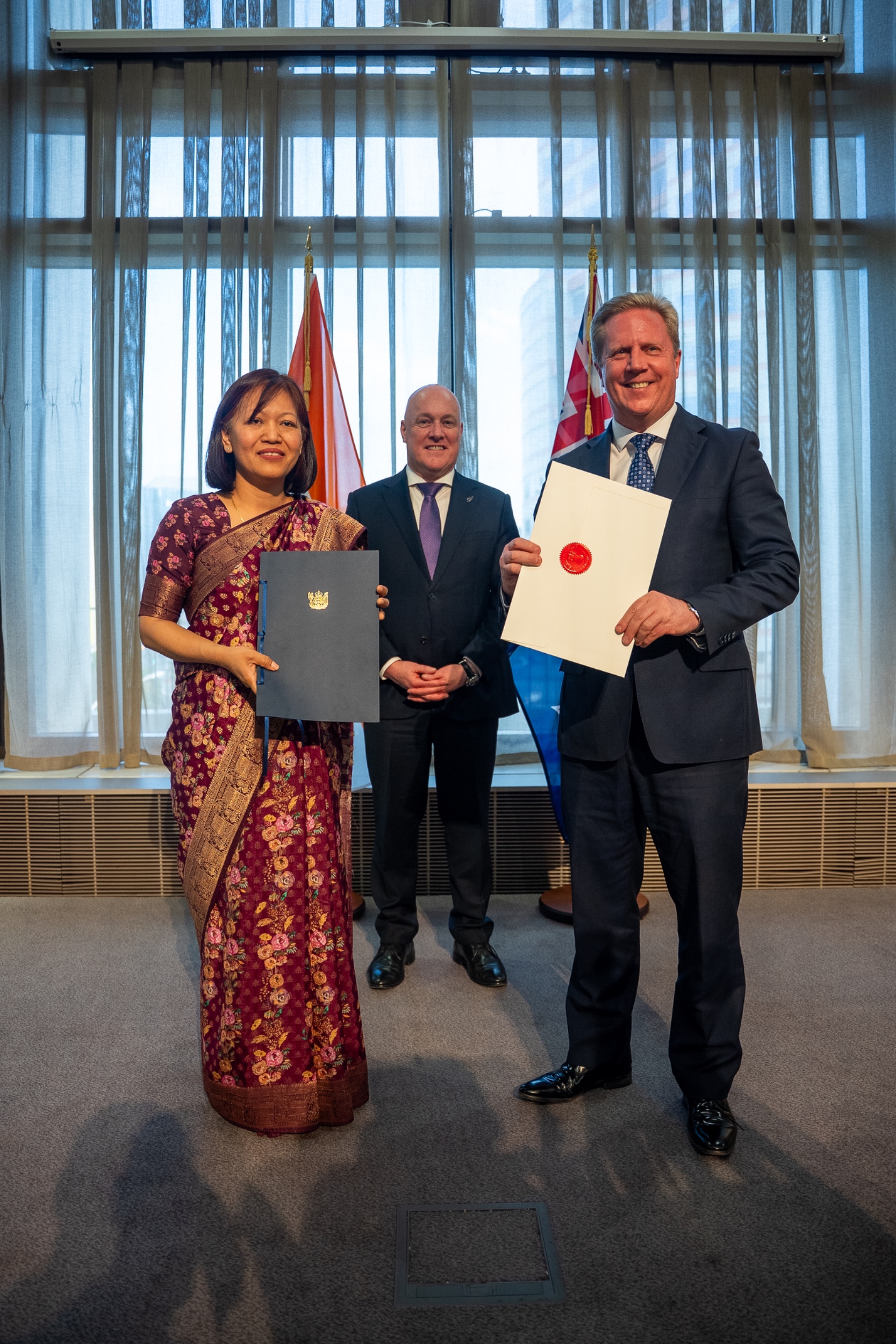 Trade minister Todd McClay exchanges ratification documents with India's high commissioner Muanpuii Saiawi in Wellington on September 21, 2026, as prime minister Christopher Luxon looks on.