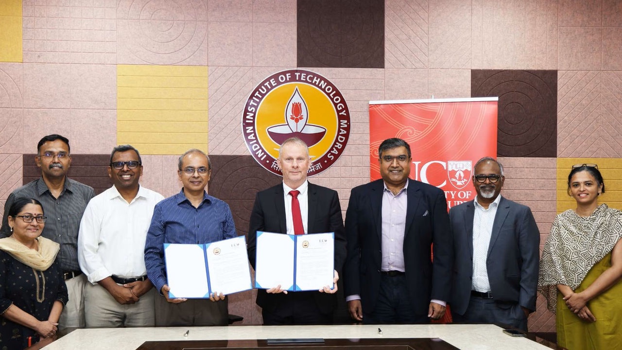 A group of eight individuals, including two women, stand behind a table holding certificates, with a logo of the Indian Institute of Technology Madras visible in the background.