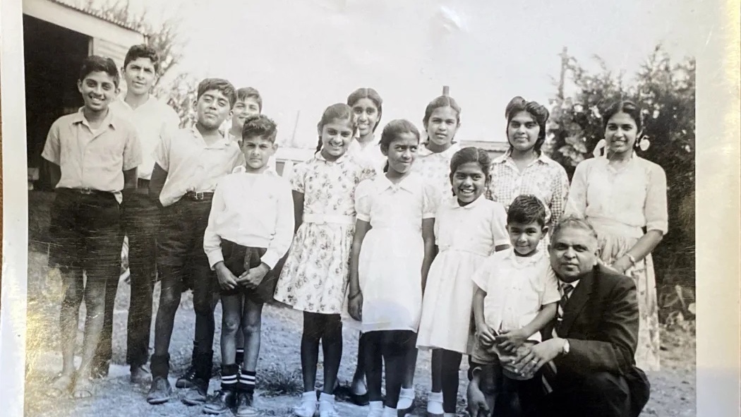 A black and white photograph of a group of children and a man, all dressed in formal attire, standing together outside a building.