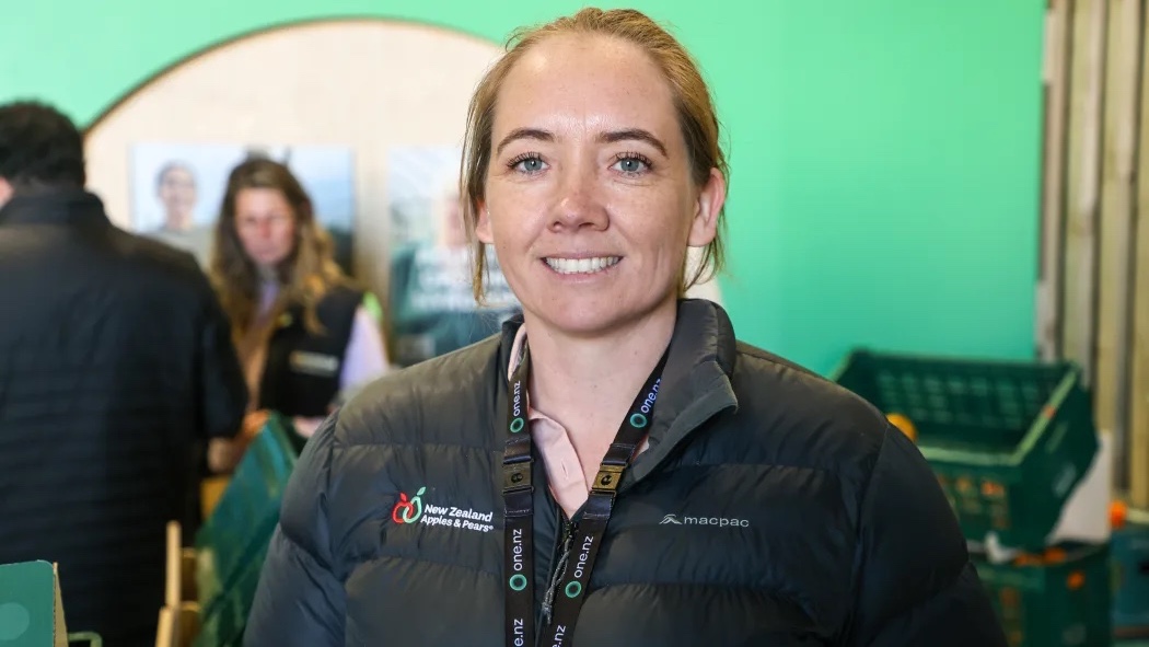 A woman wearing a black jacket with a lanyard that reads